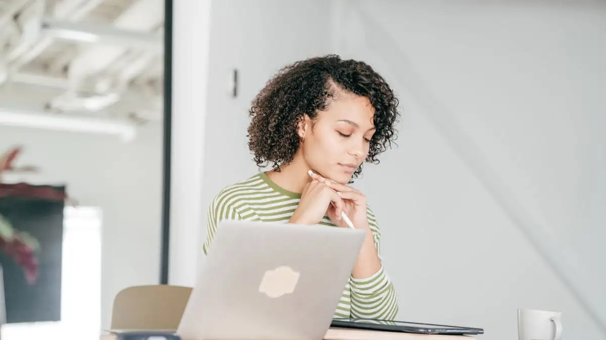 A woman in front of her laptop closing her eyes thinking about her finances