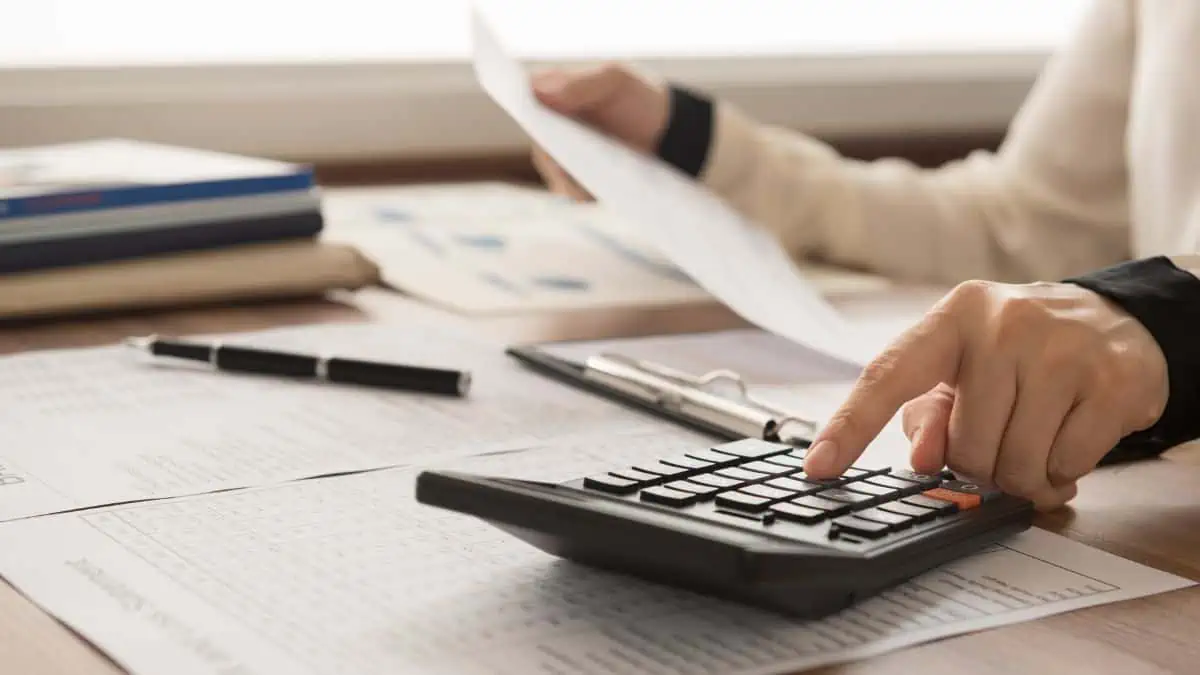 A photo of a woman with a calculator and paper in hand.