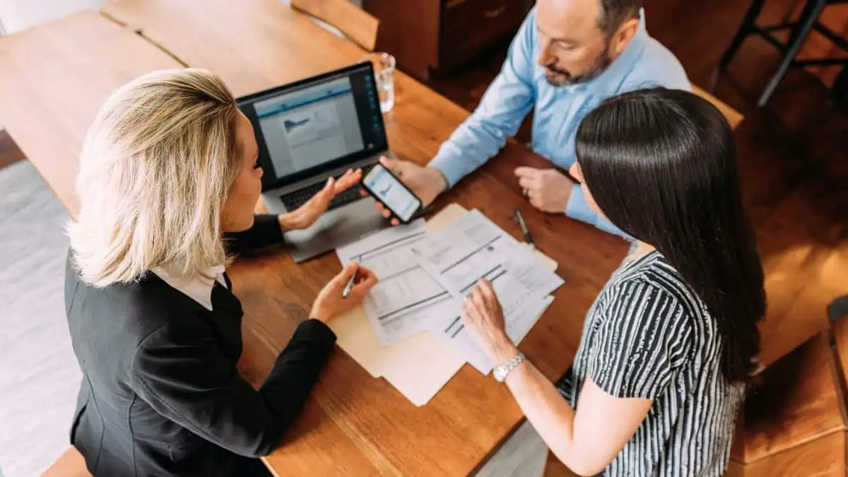 A photo of a financial advisor discussing an insurance policy to a man and woman